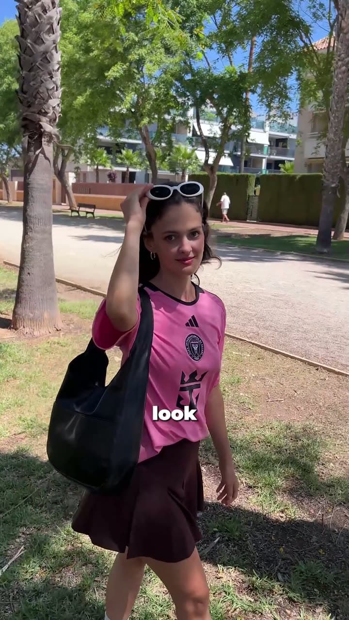 Creator in a pink football jersey on a tree-lined path