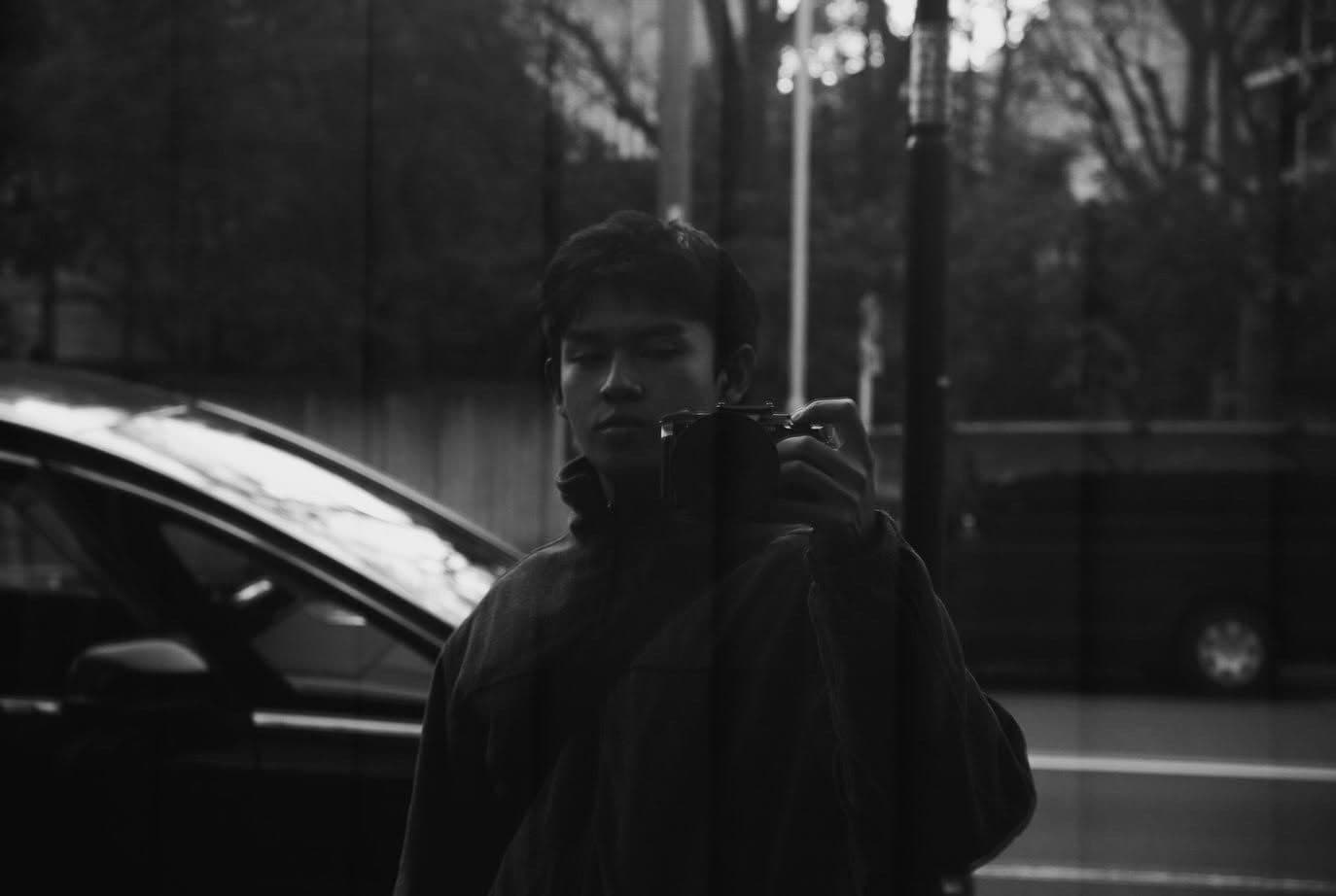 Black and white mirror self-portrait holding a camera